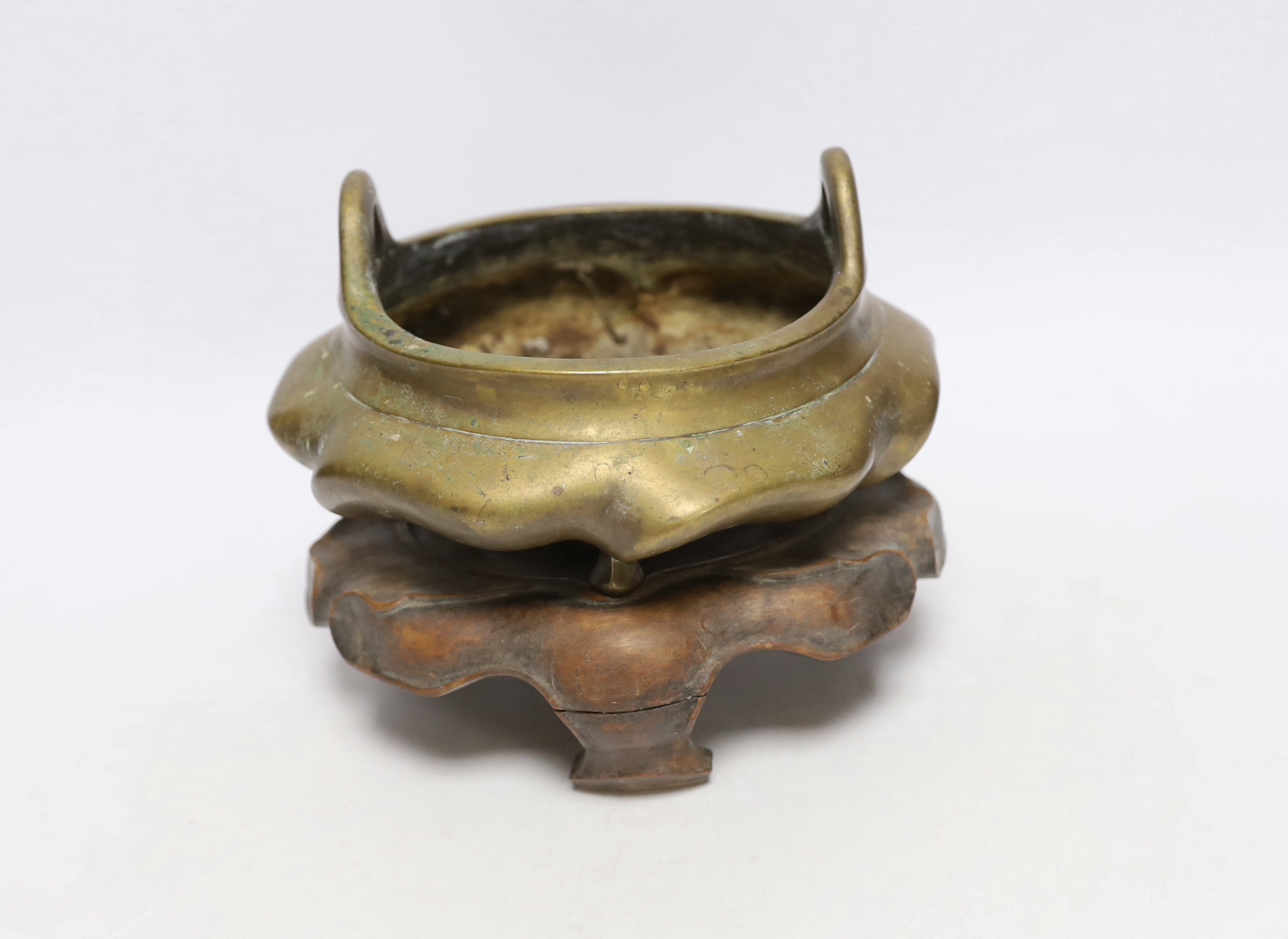 A Chinese bronze tripod censer with twin handles on hardwood stand, censer 19cm wide